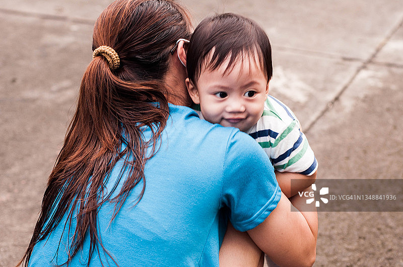 一位东南亚母亲正扶着儿子迈出第一步图片素材