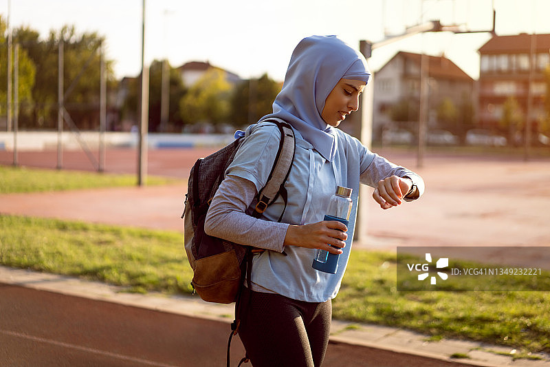 现代穆斯林女田径运动员在训练结束后，用健身追踪器检查她的脉搏图片素材