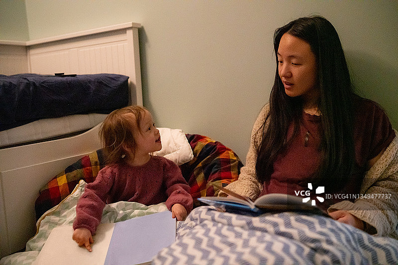母亲和孩子在卧室里读一本好书图片素材