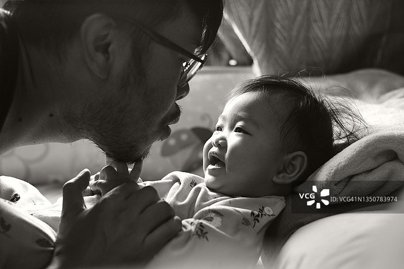 亚洲宝贝女孩和爸爸在床上玩黑白照片图片素材