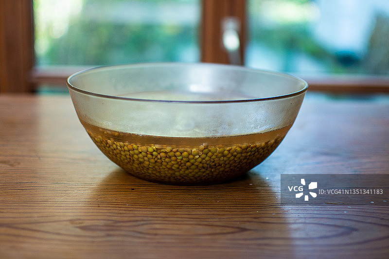 在木桌上的玻璃碗里泡扁豆。图片素材