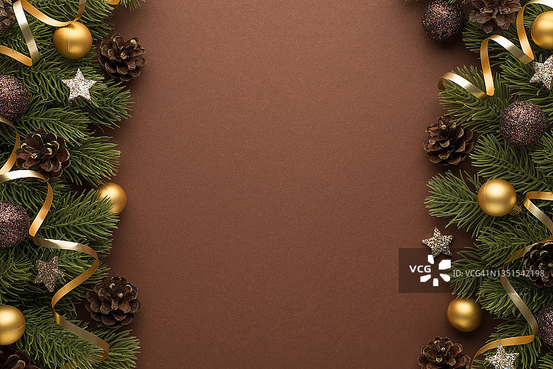 顶部视图的照片金色和棕色的圣诞树球松果发光的星星和松枝上的蛇纹石在孤立的棕色背景与copyspace图片素材