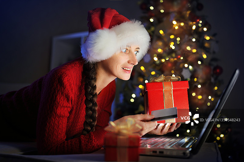 这个女孩正在为圣诞节做准备，她通过互联网为家人订购礼物。图片素材