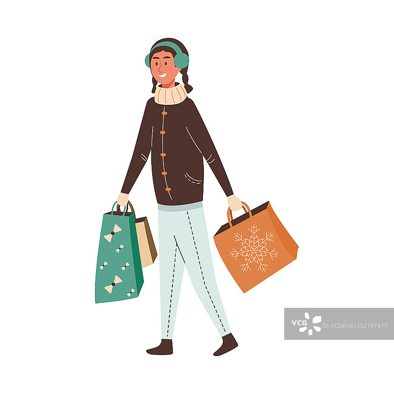 年轻可爱的女人穿着暖和的衣服，带着圣诞礼物袋在户外散步图片素材