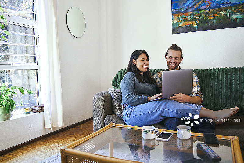 这是一对年轻夫妇在一起使用笔记本电脑放松的照片图片素材