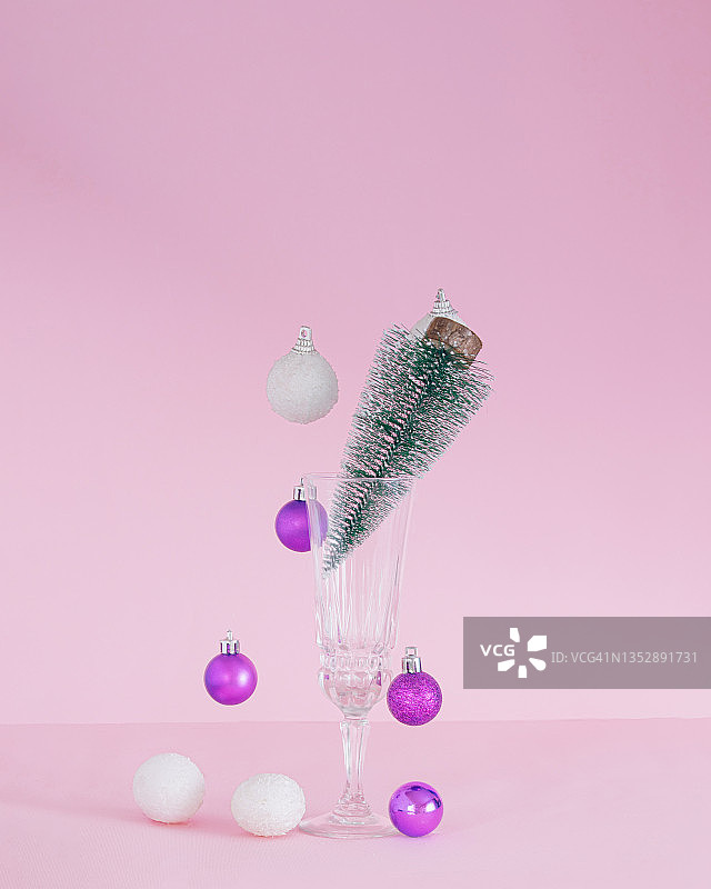 圣诞节的小玩意下来了。香槟杯里的圣诞树。装饰鲜艳的紫罗兰和雪白。新年假期概念图片素材