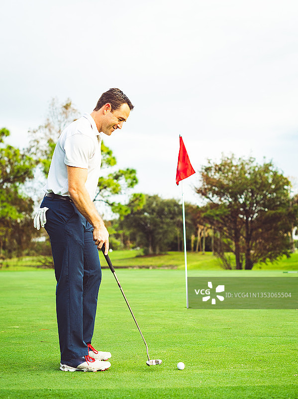 快乐的高尔夫球手在果岭上，准备击球，一杆推入最后一轮图片素材