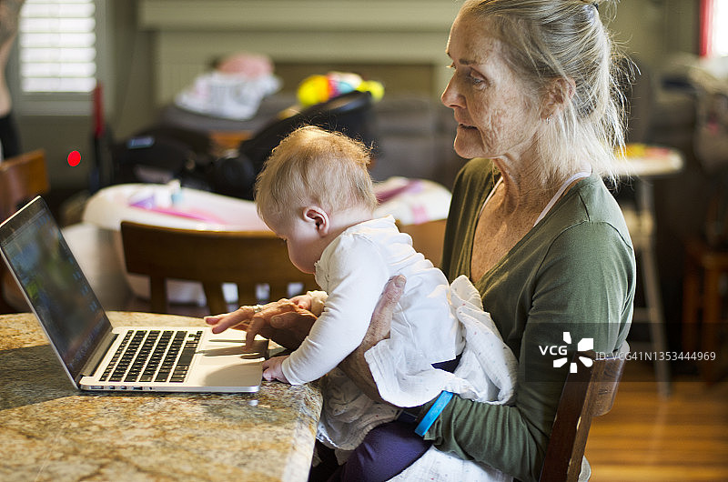 祖母抱着婴儿在电脑前图片素材