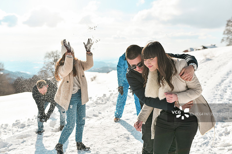 可爱的夫妇被来自朋友的一连串雪球击中图片素材