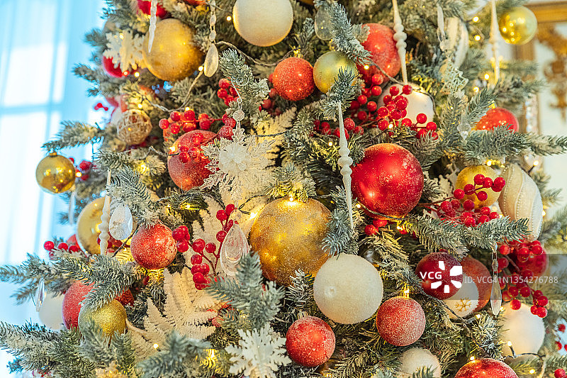 经典的圣诞新年用红色、金色和白色的装饰品装饰新年树，玩具和球。现代古典风格室内设计公寓。平安夜在家图片素材