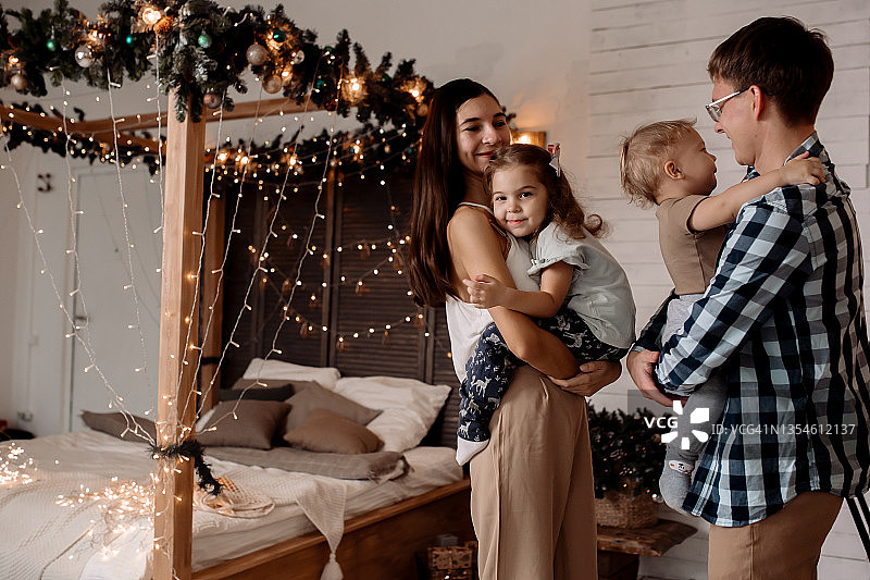 圣诞节前夕，一个美丽的小家庭在圣诞树旁图片素材