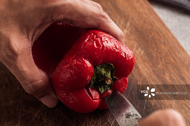 一个年轻人在切菜板上切红辣椒的特写镜头图片素材