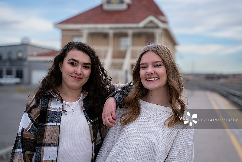 两个十几岁的姐妹一起走在火车站台上笑，享受彼此的公司在一个内城的环境图片素材