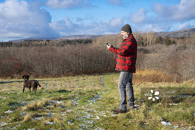 一个成熟的男人带着他的拉布拉多寻回犬在一个阳光明媚的冬日。图片素材