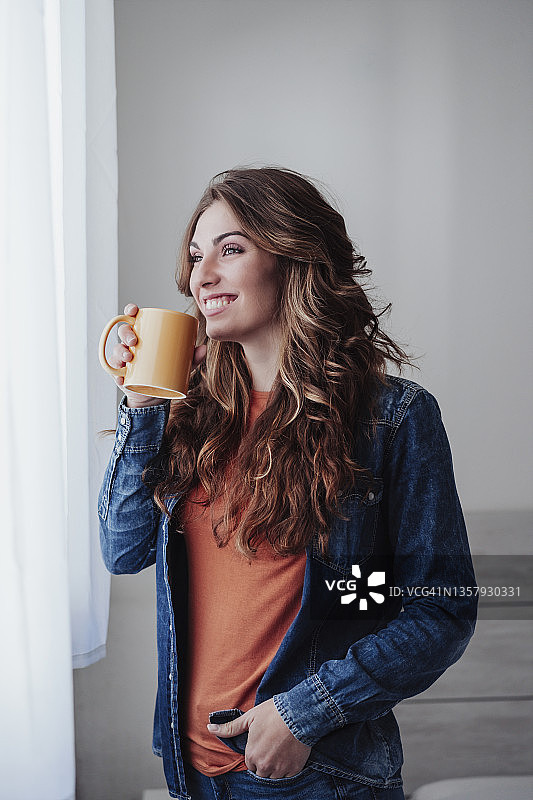 快乐的年轻女子在窗口喝咖啡图片素材