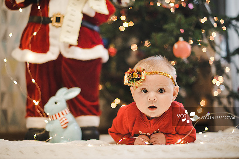 圣诞树下可爱的宝宝。图片素材
