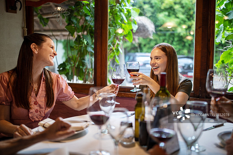 午餐时，母女俩微笑着在餐厅喝着酒图片素材