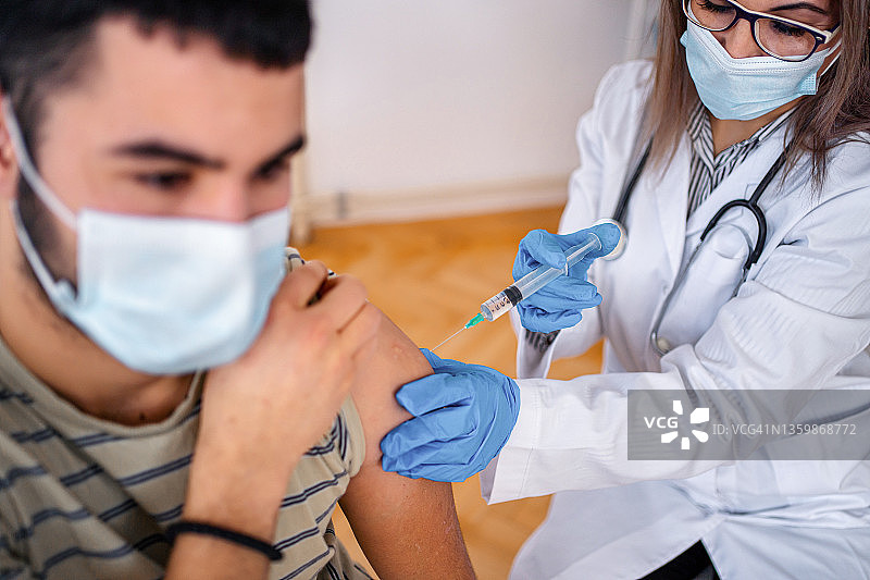 友善的医生为青少年病人接种疫苗图片素材