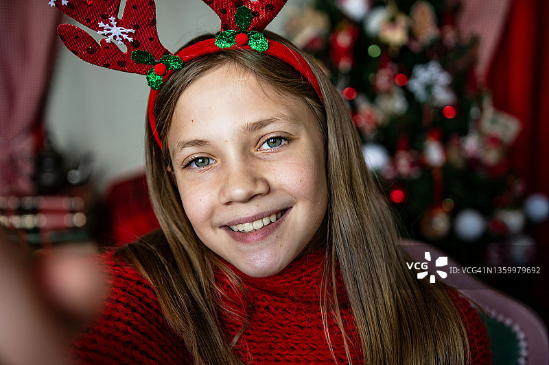 美丽的十几岁的女孩用装饰品装饰圣诞树图片素材