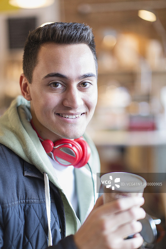 肖像微笑的年轻人喝咖啡在咖啡馆图片素材