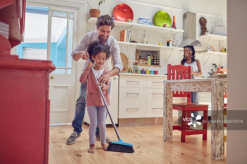 父亲和女儿用扫帚扫厨房地板图片素材