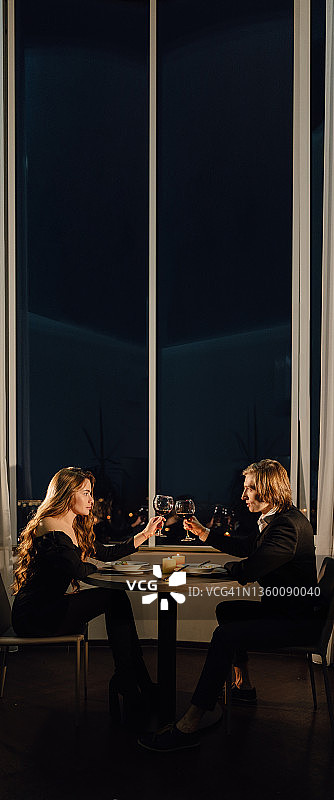 浪漫晚餐，情人节两人共进，喝红酒酒杯，情侣在餐厅用餐，约会在家，构思节日祝酒图片素材