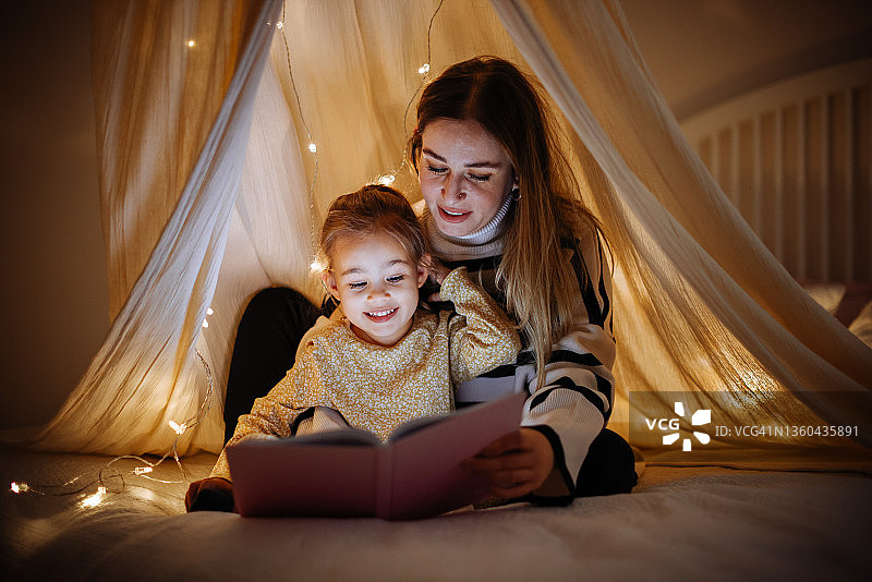妈妈和孩子睡前在床上看书图片素材