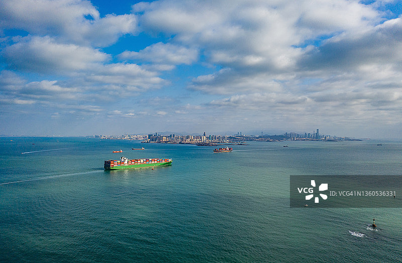 中国山东省，青岛城市天际线前的大型货船无人机视点图片素材
