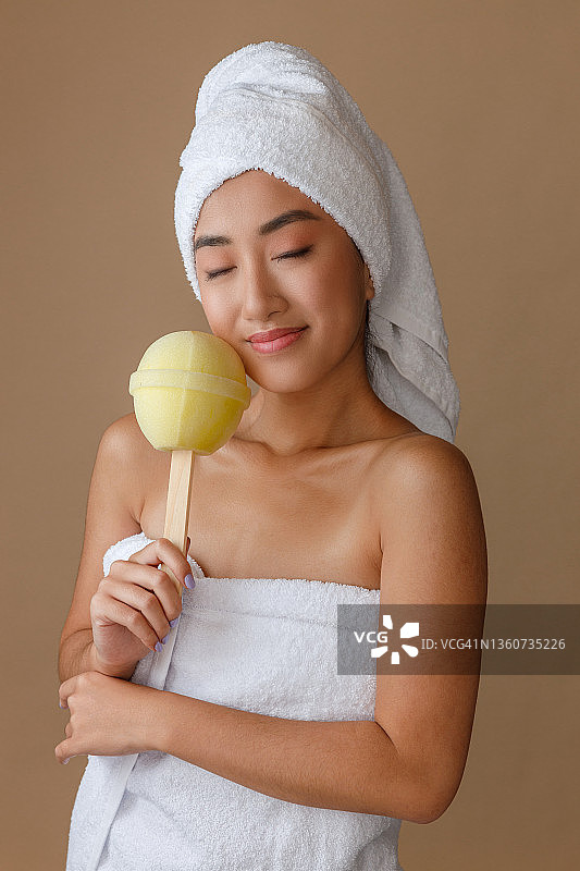 微笑的年轻女子拿着棒棒糖沐浴海绵图片素材