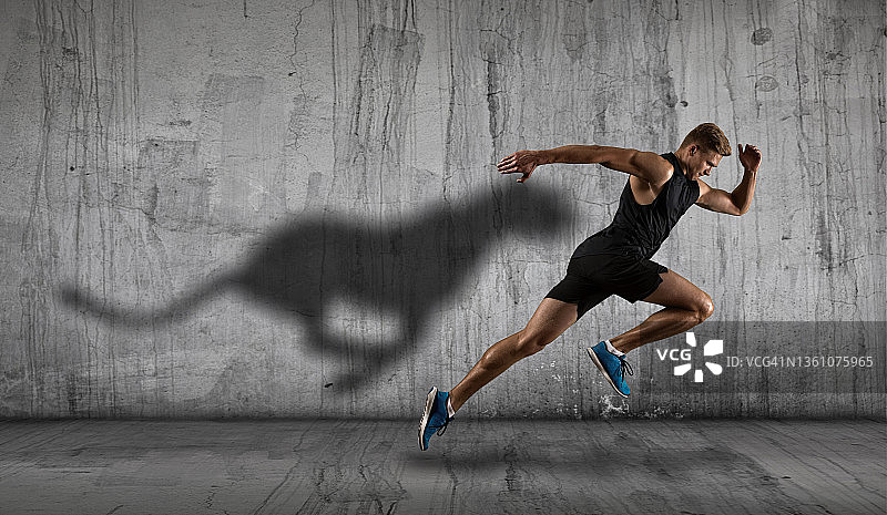 运动男子短跑运动员在黑暗的墙壁背景上运行图片素材