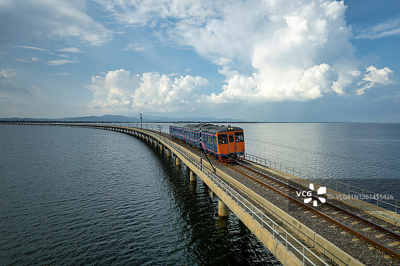 泰国中部最大的水库Pa Sak Jolasid大坝的铁路桥上的当地火车鸟瞰图。图片素材