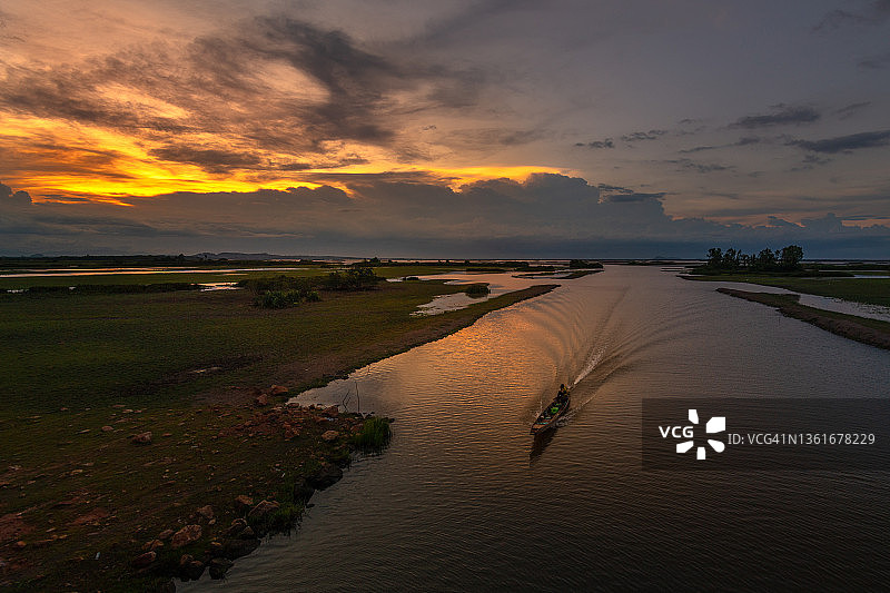 在泰国南部帕塔隆的夕阳下，渔民在白普拉河上航行图片素材