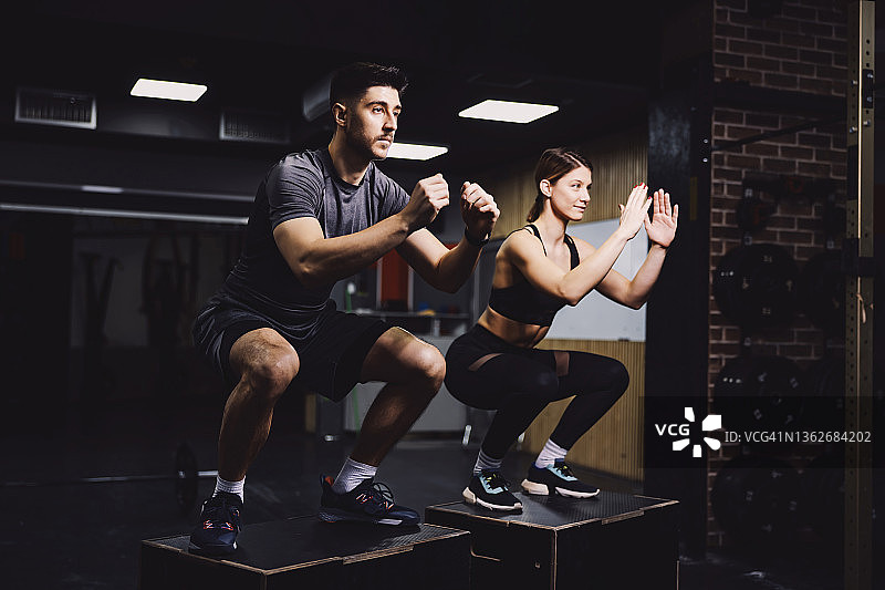一对热爱运动的夫妇在健身房做深蹲和功能性锻炼。图片素材