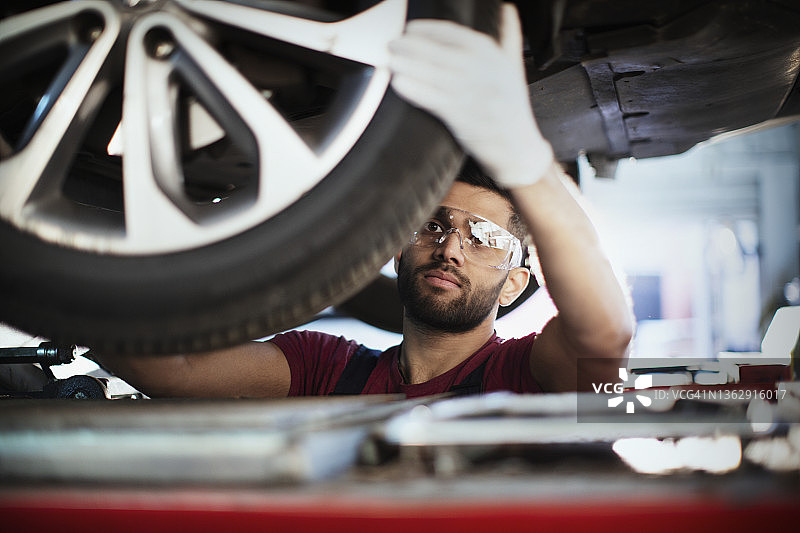 男性机械师在汽车修理店检查轮胎图片素材