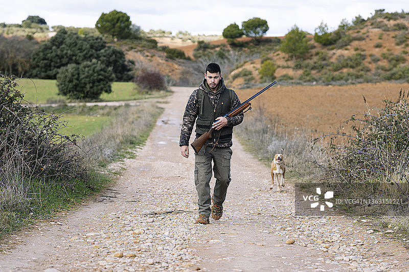 猎人带着他的狗穿过田野去打猎。图片素材