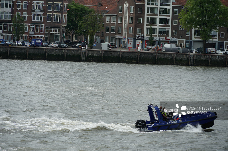蓝色的荷兰港口警察在前景的纽威·马斯河上巡逻快艇。图片素材