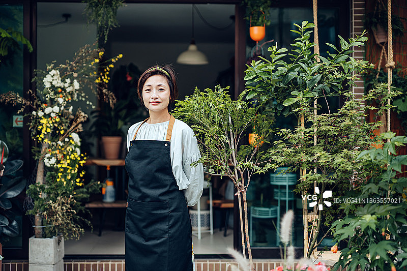 骄傲的亚洲女性花店的肖像，小生意花店的老板。微笑着站在花店外。喜欢和花在一起的工作。中小企业的概念图片素材