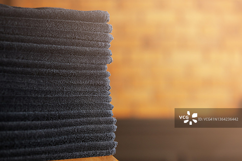 黑色浴巾堆放在木桌和砖墙背景上。spa沙龙,理发店。图片素材