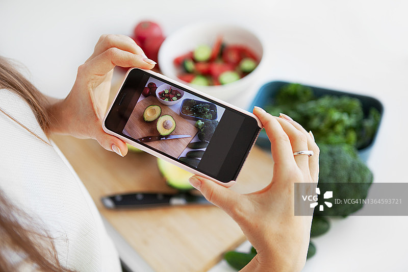 美食之手(Hands of Food)的博主用智能手机拍下放在白色背景桌子上的混合新鲜蔬菜沙拉，并在社交媒体上分享图片素材