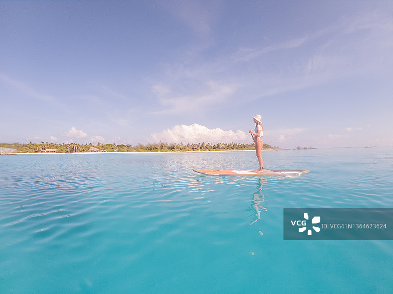 在马尔代夫站着划水的女人图片素材