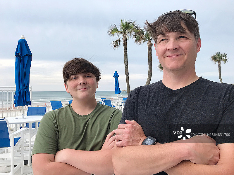 一个十几岁前的儿子和他的爸爸在海滩户外的肖像图片素材