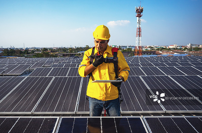 工程师手持平板站在屋顶的太阳能板上图片素材