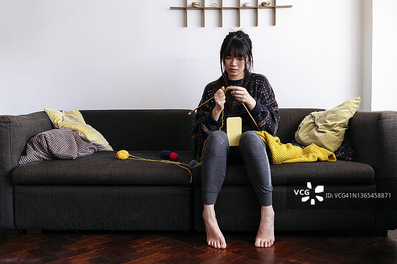 年轻女子在家用手机拍摄羊毛编织图片素材