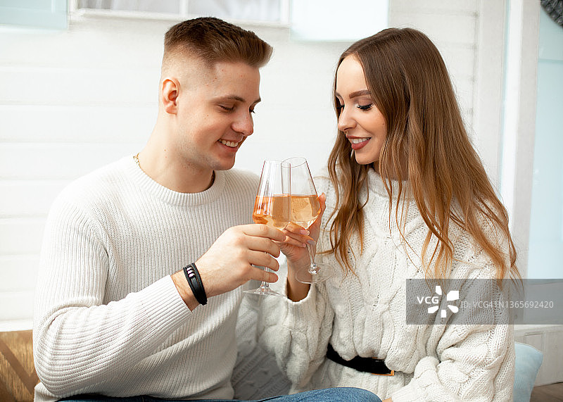 微笑的浪漫情侣穿着白色的香槟杯，庆祝节日可能是情人节图片素材