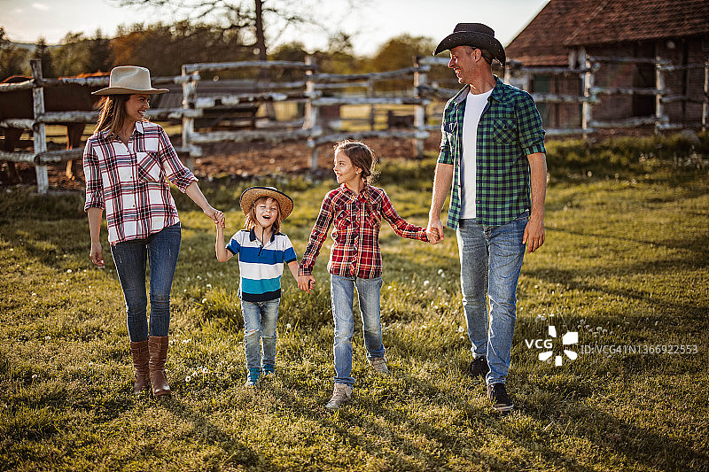 幸福的一家人在牧场上散步。图片素材