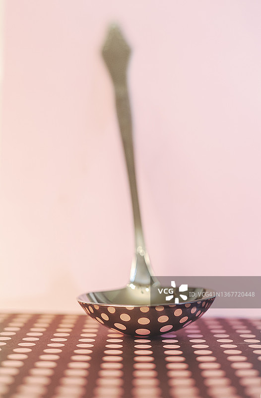 分发食物的勺子，有几何图形的反射，粉红色的背景。图片素材