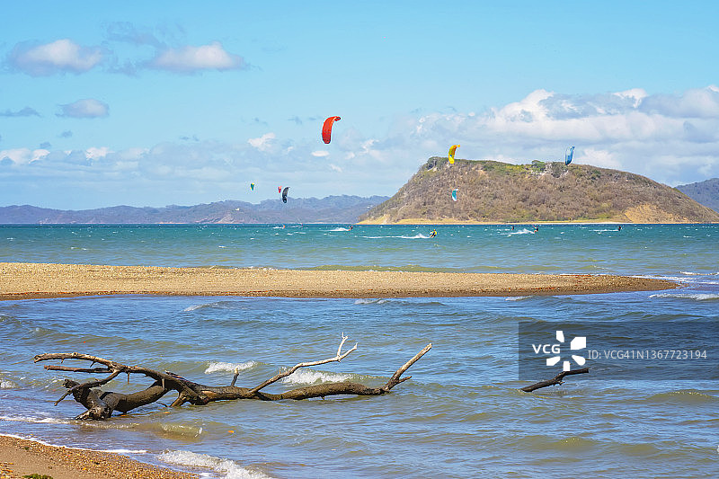 在哥斯达黎加，人们在海上对着山脉和天空玩风筝滑板时看到的海滩景色图片素材
