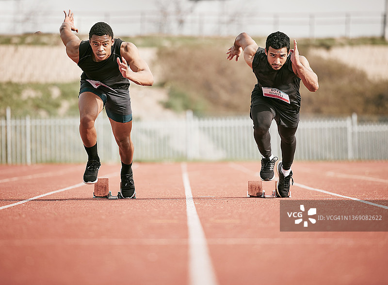 两个英俊的年轻男性运动员在跑道上开始他们的比赛的全长镜头图片素材