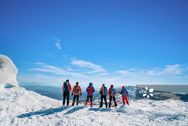 高山登山队正在冬季观看高海拔山峰的风景图片素材