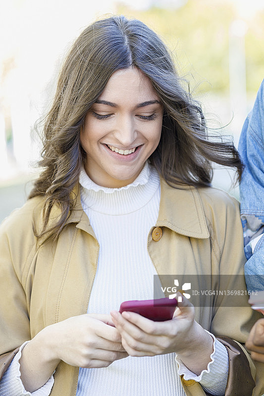 微笑的女人在大学校园里使用智能手机图片素材